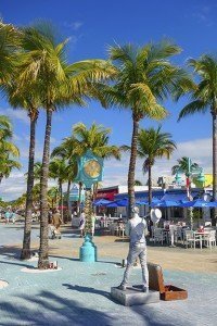 A living statue poses at the Fort Myers Beach street clock with pedestrians walking by in the background.