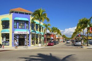 Pedestrians walking past colorful businesses on Old San Carlos Boulevard, in the central shopping and dining district of Fort Myers Beach, Florida.