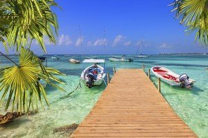 wooden pier and fishing boats on a Caribbean beach with transparent waters