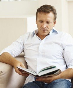 Handsome middle aged man reading a book at home