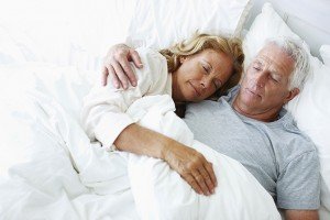 Relaxed elderly couple lying in bed together and sleeping