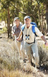 A shot of a senior man pulling his wife by the hand while walking in the forest